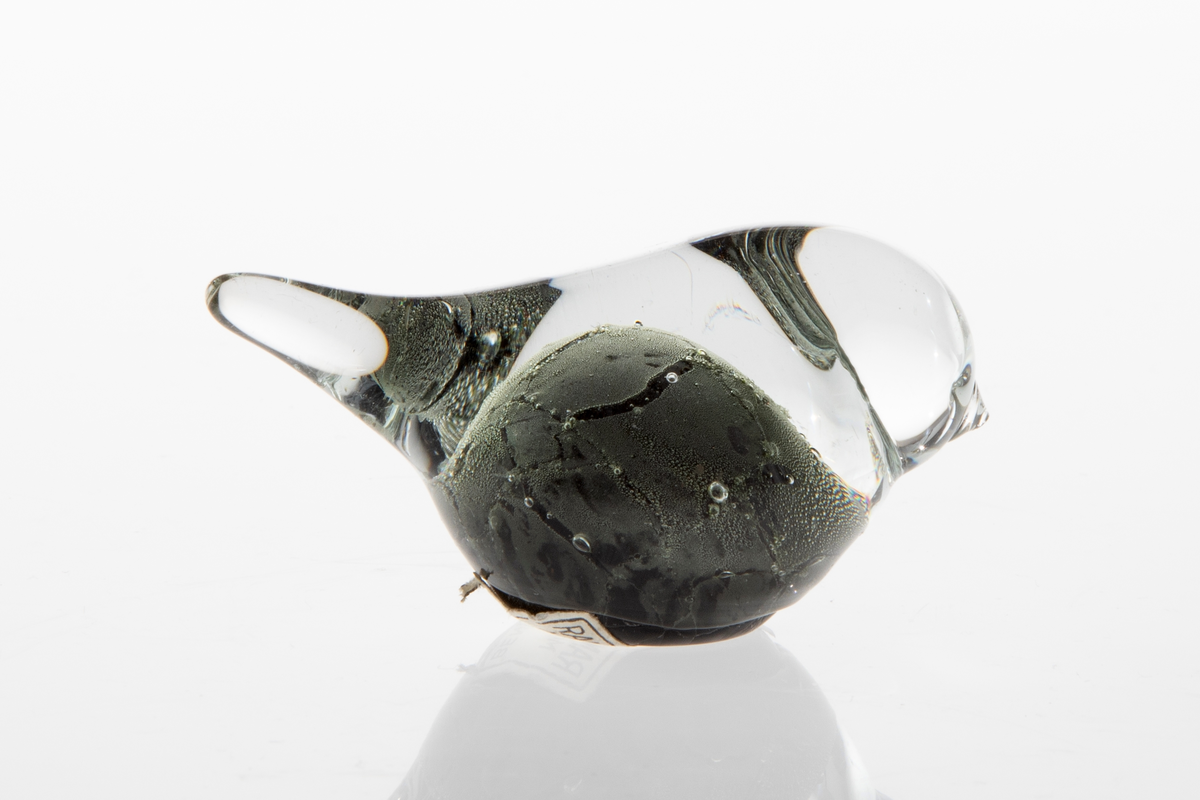 Glassfigur i klart og sortfarget opakt glass. Stilisert fugleform samt luftbobler.