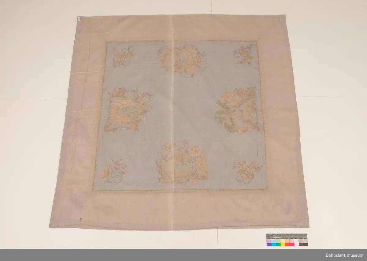 Silkebroderi på ljusblått siden.

Broderiet daterades till 1916-1917 och har varit utställtpå Röhsska Konstslöjdmuseet, Göteborg 1918 och visades också 2019 i separatutställningen Birger Simonsson på Bohusläns museum 2019.

Till duken hör en äldre etikett lagad med tejp med handskriven text: Broderad sidenduk av I.S. utförd 1916-17. Utställd på Röhsska museet 1918.