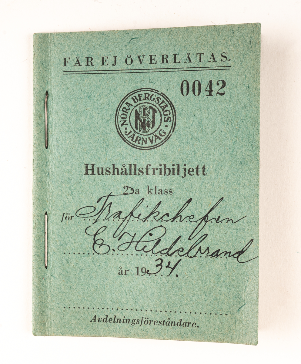 En samling hushållsfribiljetter tilldelade trafikchef E. Hildebrand 1934. Ett grönblått häfte med 8 sidor om vardera 12 fribiljetter för tågresor. Tryckt text på framsidan: "FÅR EJ ÖVERLÄMNAS. 0042 NORA BERGSLAGS JÄRNVÄG Hushållsfribiljetter 2:a klass för ... år 19... Avdelningsföreståndare." Handskrivet "Trafikchefen E. Hildebrand" och "34".