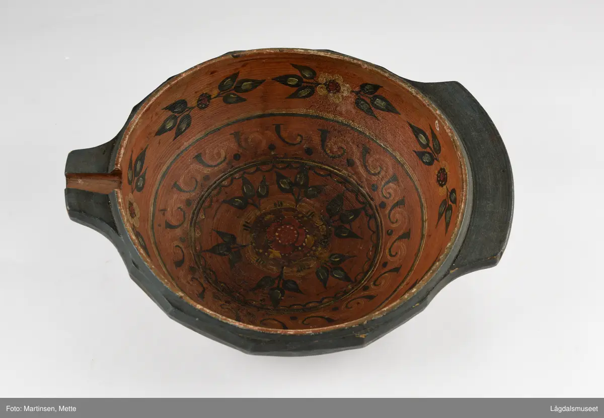 Dreid øltrøys utvendig malt ensfarget rødbrun. Innvendig i bunnen symmetriske blomstermotiv, sirkelrundt. I felt rundt bord med liggende S-former. Øverst mot kanten bord seks stiliserte blomstermotiv