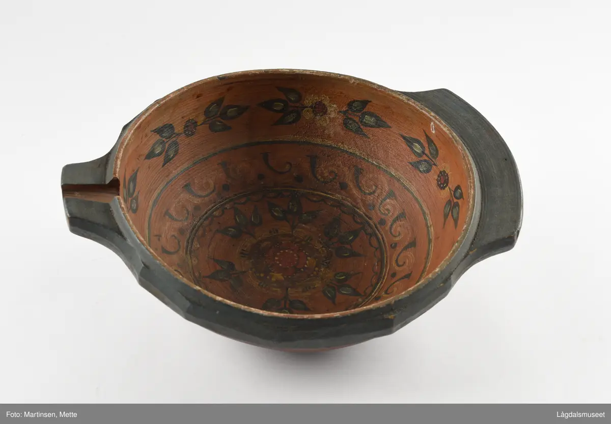 Dreid øltrøys utvendig malt ensfarget rødbrun. Innvendig i bunnen symmetriske blomstermotiv, sirkelrundt. I felt rundt bord med liggende S-former. Øverst mot kanten bord seks stiliserte blomstermotiv