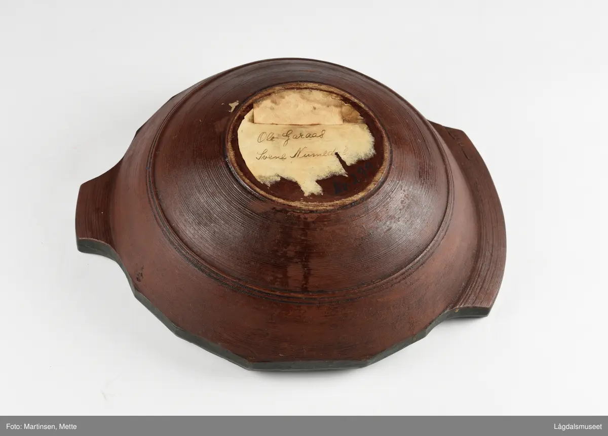 Dreid øltrøys utvendig malt ensfarget rødbrun. Innvendig i bunnen symmetriske blomstermotiv, sirkelrundt. I felt rundt bord med liggende S-former. Øverst mot kanten bord seks stiliserte blomstermotiv