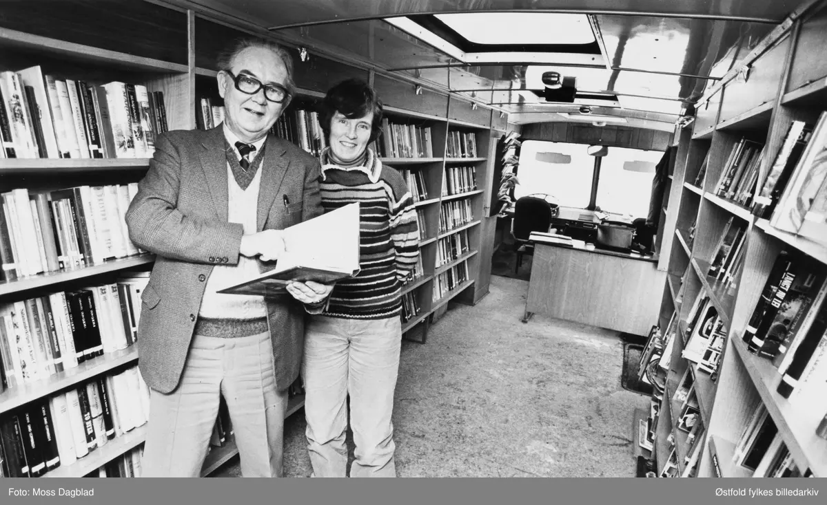 Bokbussjåfør og bibliotekfullmektig Viggo Nilsen og bibliotekfullmektig Turid Pettersen i bokbussen til Østfold fylkesbibliotek på Øreåsen i Rygge, 8. januar 1980. Bussen sto parkert utenfor Roars butikk, omen det kom ikke mange folk denne formiddagen. Dette var nemlig  første gang bokbussen besøkte Øreåsen. Nilsen hadde tro på at besøket ville bli større når det ble bedre kjent.