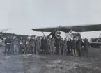 Gruppfotografi av militära flygare framför flygplan S 6 på ett flygfält, omkring 1934-1936.

Tredje man från vänster är Nils-Olof Svensson (Sefeldt).

Text vid foto: 