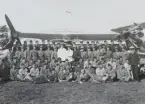 Gruppfotografi av deltagare vid arméspaningskursen, 1934. Lärare, elever och flygtekniker samlade på flygfältet framför hangar 81 på F 3 Malmen. Tre flygplan S 6 Fokker omgärdar dem.

Text vid foto: 