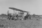 Flygplan S 6 nr 3381 under prov av kulspruta, ståendes på ett flygfält, omkring 1935-1936. Flygare på plats i förarhytt och mekaniker runt flygplanet.

Text vid foto: 