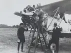 Kontroll av flygplan S 6 Fokker på ett flygfält, omkring 1934-1937. Två flygmekaniker står på stege i arbete med motorn, en uniformsklädd militär kontrollerar motorn från marken. Till höger står flygfotograf Bernhard Jernberg.

Text vid foto: 