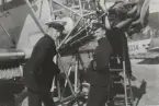 Två militärer står vid motorn på flygplan S 6 Fokker på ett flygfält, omkring 1935. Mannen till höger är Nils Olof Svensson (senare Sefeldt).

Text vid foto: 