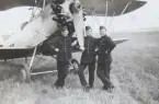 Tre militära flygare står vid nosen på flygplan Ö 9, ASJA Typ 2 på ett flygfält, omkring 1935. Mannen till vänster är Nils Olof Svensson (senare Sefeldt).

Text vid foto: 