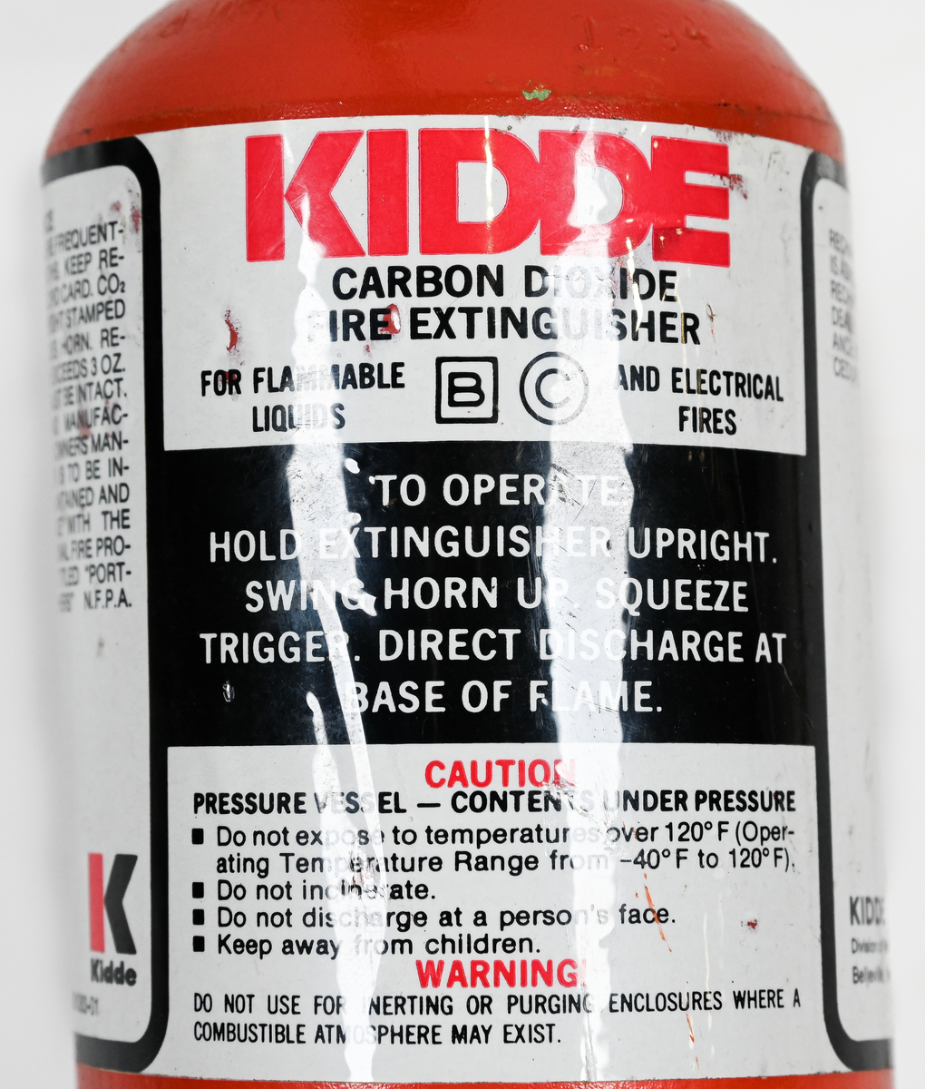 Kolsyresläckare. rödmålad, i metall med vridbar slang och aktiveringsknapp, modell 2TA. Tillverkad av Kidde i Belleville, New Jersey och använt av Linjeflyg. Första inspektionsdatum är 1975 och sista är 1985-10-04. Total vikt ifylld: 3395 gr.