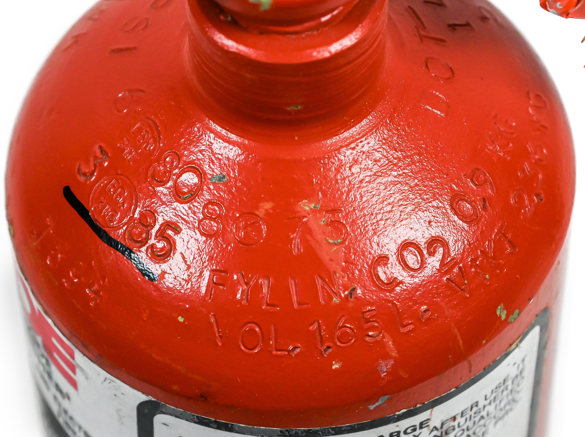 Kolsyresläckare. rödmålad, i metall med vridbar slang och aktiveringsknapp, modell 2TA. Tillverkad av Kidde i Belleville, New Jersey och använt av Linjeflyg. Första inspektionsdatum är 1975 och sista är 1985-10-04. Total vikt ifylld: 3395 gr.