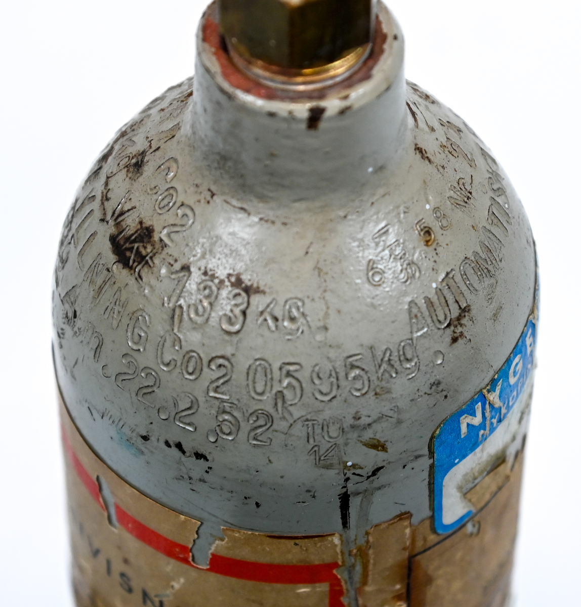 Kolsyreflaska i silverfärgad metall, förmodligen ansett som en del av en brandsläckare system. Flaskan är märkt som tillverkad av De Förenade Kolsyrefabrikernas AB 1/3/1952 och med sista inspektion av Swedish Airworks LTD 27/02/1974. På sidan finns det instruktion för hantering av föremålet som gasflaska på ena sidan och som brandsläckare på andra sidan. Fylld vikt: 1.31 kg. Prägling som attesterat att flaskan fick inspektion 1958, 1965 och 1972.