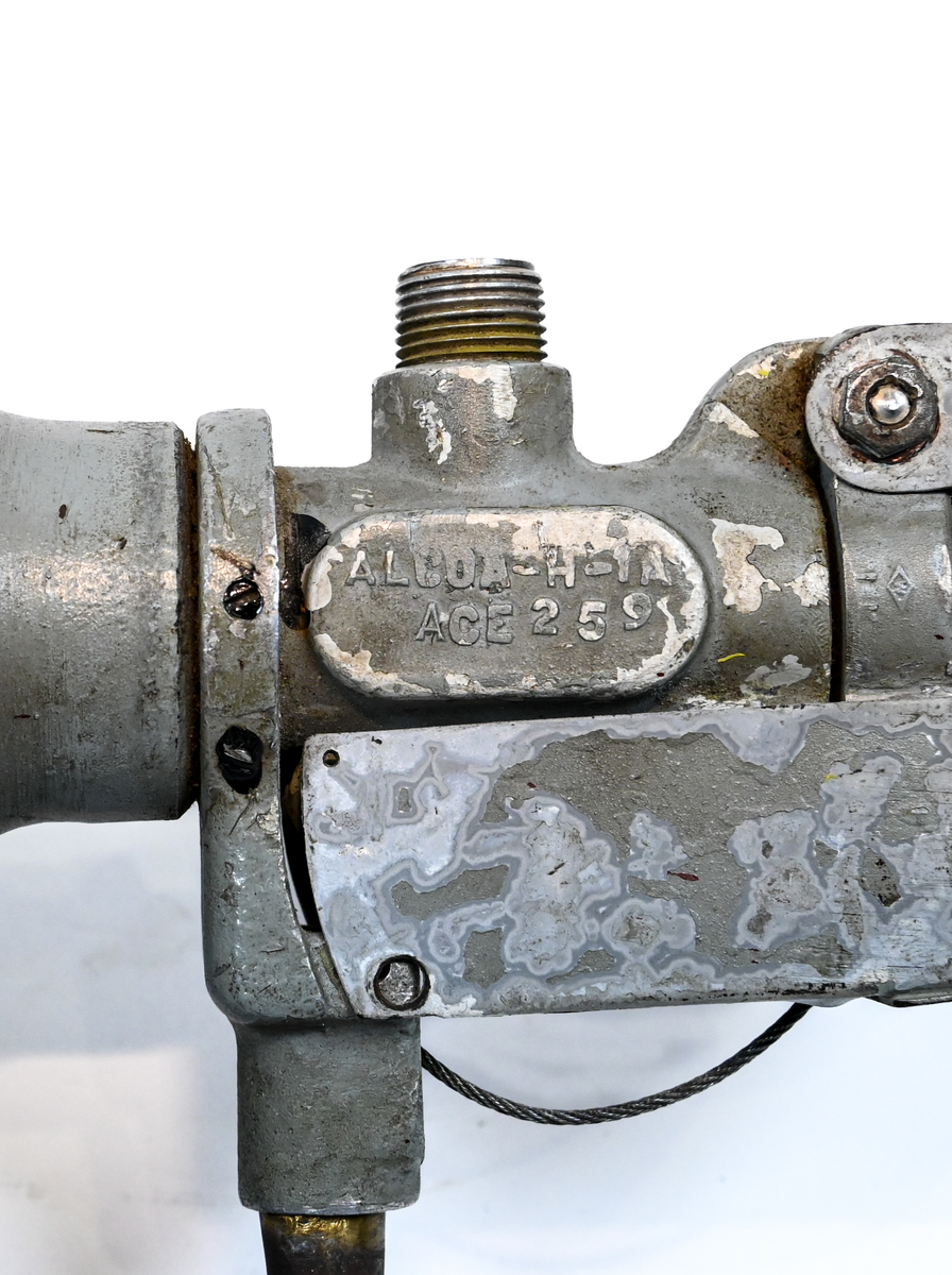 Kolsyresläckare i gråfärgad avrundad metall flaska med ventil, lösningshandtag och slang i fiber och läder, tillverkad av De Förenade Kolsyrefabrikernas AB. På föremålet står det ABA Typ-501-32-02-1. Tillsynsdatum präglat på flaskan 10/40 och 07/46.