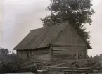 Här ser vi det mycket gamla huset från andra håller. Baksidan är blind, här finns bara en dörr, vilken kan ha gått till ett minimalt kök på husets baksida, iom att man lagade mat över öppen eld, behövde man inte kosta på sig ett fönster. Möjligen kan det vara ett igensatt fönster längst bort mot hörnet tillhörigt vardagsstugan. Salen hitåt har bara ett fönster på gaveln. Så fönsterfattiga var bostadshusen för 250-300 år sedan. Väggarnas bular är hellängdare utan skarvar, vilket också är ett mycket gammalt tecken. Dörrposterna fungerade här som mötare, stående stolpar där bularna skarvades.