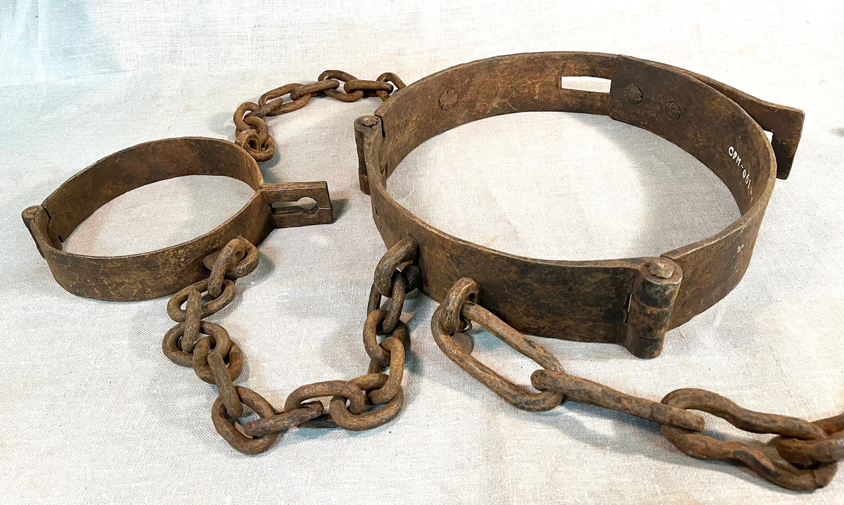 Svært kraftig fangejern bestående av halsring og midjejern. Halsringen er hengslet og festet tilmidjejernet med to lenker. Lenkene har 11 og 13 ledd. Midjejernet er tredelt, har to hengsler, og endestykker, det ene med tre hull, det andre med tre kramper, så jernet kan justeres etter fangens midjemål. Fra livringens bakside går en lenke på 25 ledd, for feste i vegg e.l.