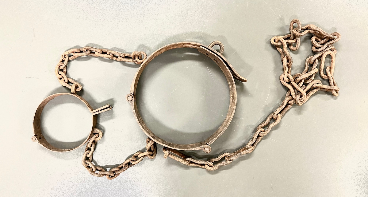 Svært kraftig fangejern bestående av halsring og midjejern. Halsringen er hengslet og festet tilmidjejernet med to lenker. Lenkene har 11 og 13 ledd. Midjejernet er tredelt, har to hengsler, og endestykker, det ene med tre hull, det andre med tre kramper, så jernet kan justeres etter fangens midjemål. Fra livringens bakside går en lenke på 25 ledd, for feste i vegg e.l.