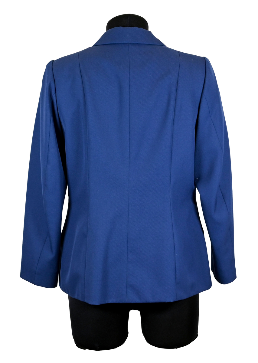 Kavaj i mörklbå ull- och polysterblandning till ämbetsdräkt för kvinnlig personal vid Luftfartsverket. Fodret är gjort i mörkblå polyester. Kavajen har två framfickor med lock som fortfarande är igensydda samt en innerficka vänster sida som stängs med plastknapp. Kavajen stängs med metallknappar med Luftfartsverkets logga i relief. 

På insidan ovanför innerfickan sitter en lapp med Luftfartsverkets logga samt information om tillverkare och designer. I anslutnings till den sitter en mindre lapp med storleksangivelser. Kavajen producerad av Confetti och designad av Morgan i storlek C42. På insidan i ena sidosömmen sitter ytterligare en lapp med tvättanvisningar och information om material och tillverkningsort. Kavajan är tillverkad i Estland. I denna lapp sitter en extra metallknapp samt en fasthäftad papperslapp med numret "8632" i tryck och "3/10" påskrivet i blått bläck.