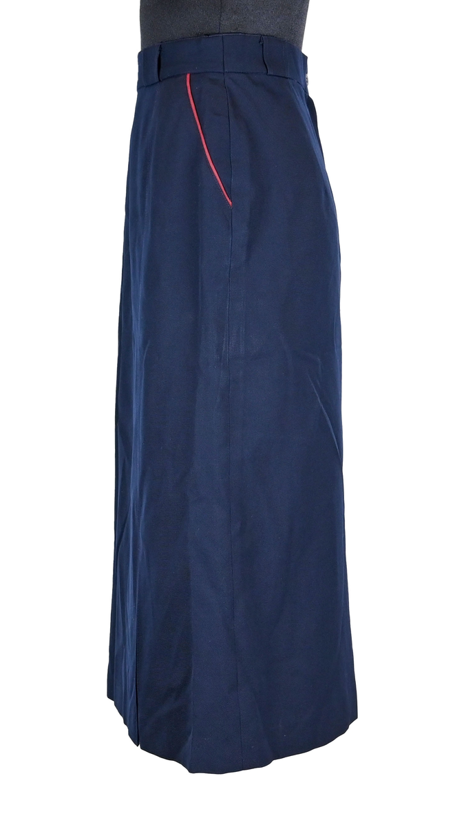 Kjol för flygbolagspersonal på Linjeflyg. Mörkblå snäv modell med slitsar och veck för vidd nertill. Med vinröda passpoaler på fickornas kanter. Märkt ”Linjeflyg”.