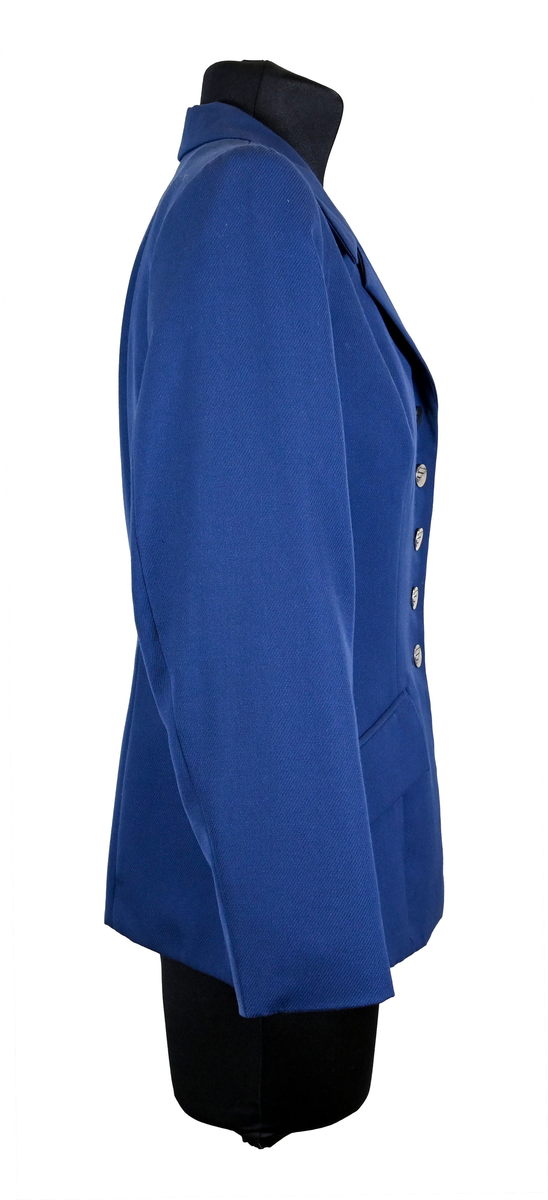 Kavaj i mörklbå ull- och polysterblandning till ämbetsdräkt för kvinnlig personal vid Luftfartsverket. Fodret är gjort i mörkblå polyester. Kavajen har två framfickor med lock som fortfarande är igensydda samt en innerficka vänster sida som stängs med plastknapp. Kavajen stängs med metallknappar med Luftfartsverkets logga i relief. 

På insidan ovanför innerfickan sitter en lapp med Luftfartsverkets logga samt information om tillverkare och designer. I anslutnings till den sitter en mindre lapp med storleksangivelser. Kavajen producerad av Confetti och designad av Morgan i storlek C42. På insidan i ena sidosömmen sitter ytterligare en lapp med tvättanvisningar och information om material och tillverkningsort. Kavajan är tillverkad i Estland. I denna lapp sitter en extra metallknapp samt en fasthäftad papperslapp med numret "8632" i tryck och "3/10" påskrivet i blått bläck.