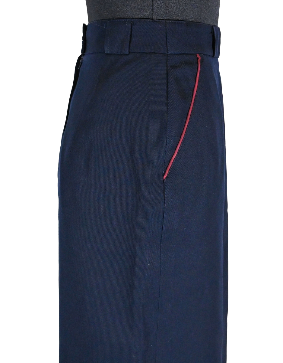 Kjol för flygbolagspersonal på Linjeflyg. Mörkblå snäv modell med slitsar och veck för vidd nertill. Med vinröda passpoaler på fickornas kanter. Märkt ”Linjeflyg”.