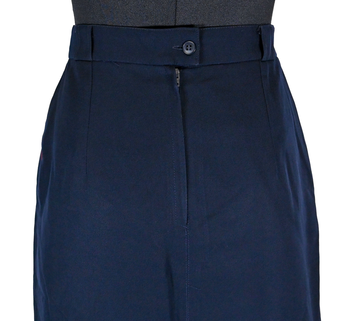 Kjol för flygbolagspersonal på Linjeflyg. Mörkblå snäv modell med slitsar och veck för vidd nertill. Med vinröda passpoaler på fickornas kanter. Märkt ”Linjeflyg”.