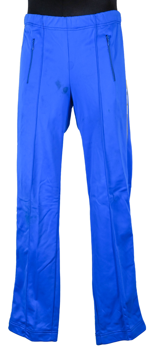 Byxa till träningsoverall. Plagget är gjort av tyg i polyamid och triacetat. Byxan är blå med smala bårder i gult tyg längs med benens yttersida. Inuti finns foder i vitt tyg. På vardera sida i fram finns två byxfickor som sluts med blå dragkedja i metall och plast. I midjan sitter ett resårband. 

Enligt en lapp fastsydd i sömmen bak på byxans insida är plagget producerat av Yngve Ek, Höör Sweden. Där finns även två identiska lappar som anger att byxan är gjord av 45% polyamid och 55% triacetat. Där finns även tvätthänvisningar.

Byxan är en del av en tävlingsoverall för svenska landslaget i hängflygning tillsammans med jacka AFS2508.