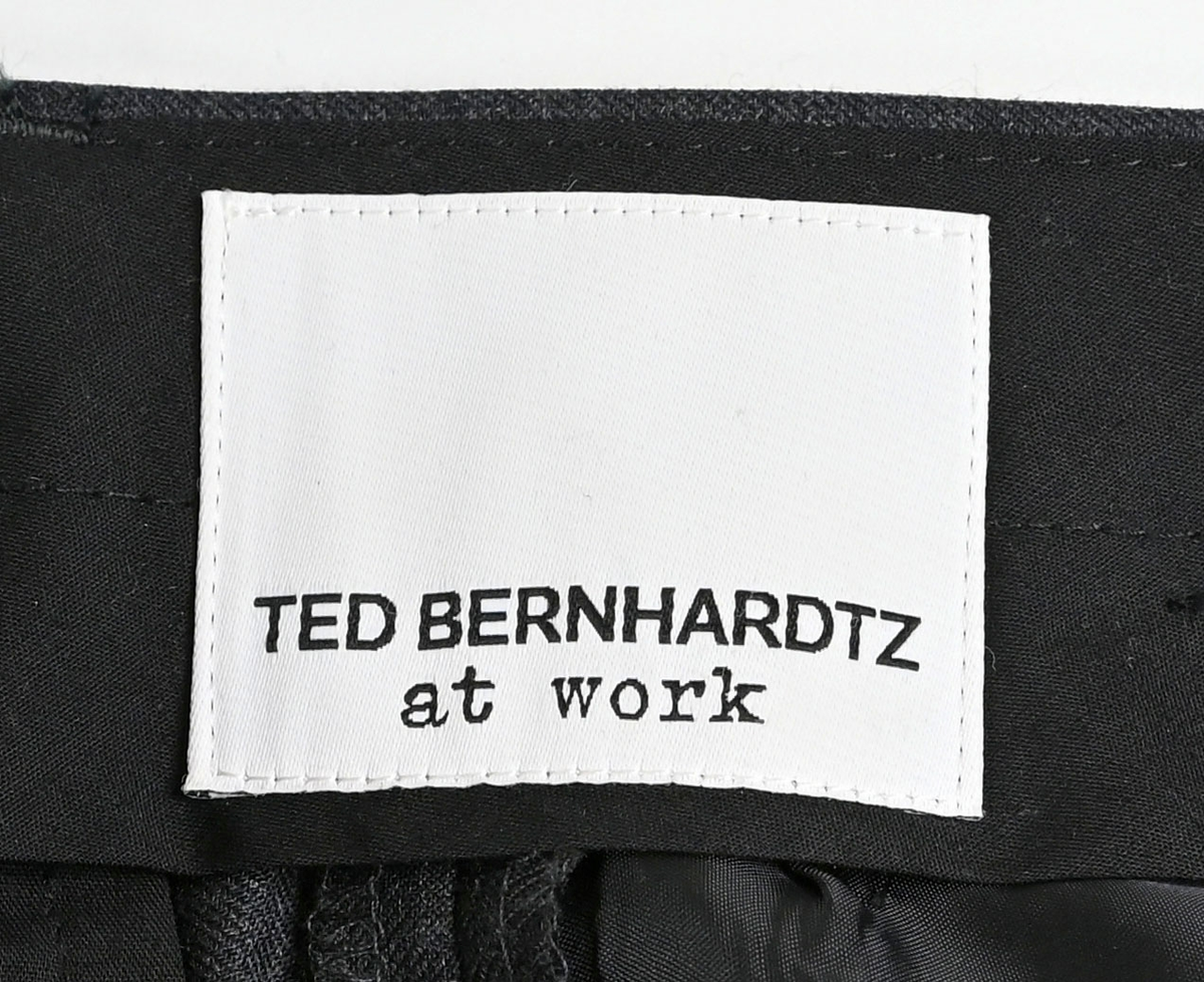 Byxa i mörkgrå ull- och polyesterblandning till uniform i dammodell för flygbolagspersonal. Byxan har två enkla fram- och bakfickor. Öppningen till bakfickorna är fortfarande igensydda. Innerfodret är gjort i svart tyg. Längs midjan sitter sex hällor för bälte. Gylfen stängs med dragkedja, krokknapp och plastknapp. Byxan är gjord i storlek 36. 

På insidan i linningen sitter en lapp som anger att byxan är producerad av Ted Bernhardtz At Work, samt en lapp med storlek. I ena sidosömmen sitter en lapp med information om plagget samt tvättanvisningar.