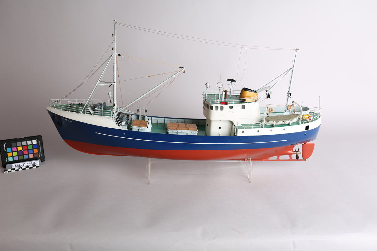 Modell av havfiskefartøy. Det er et anker på hver side av baugen. På dekket bak styrehuset er det en livbåt og en redningsflåte. På det nedsenkede dekket foran styrehuset er det to lasteluker. Båten har kraftblokk og kran.