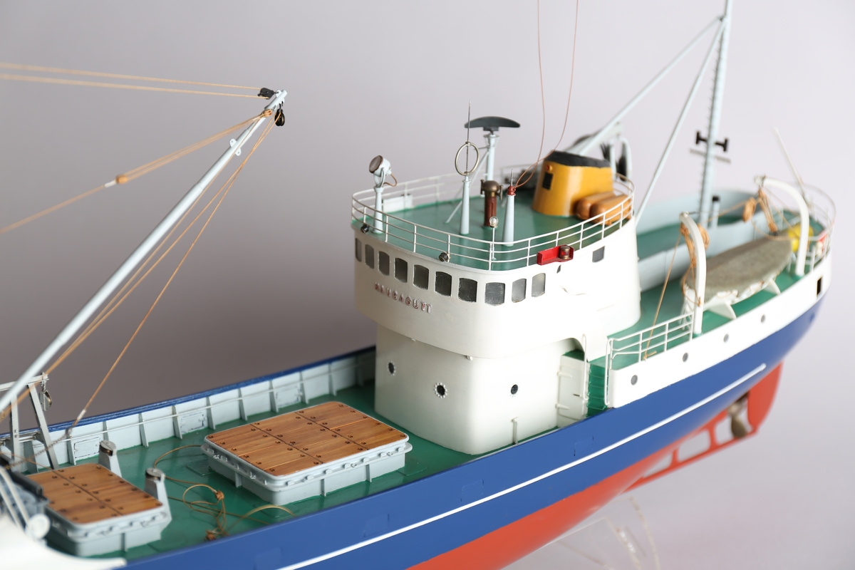 Modell av havfiskefartøy. Det er et anker på hver side av baugen. På dekket bak styrehuset er det en livbåt og en redningsflåte. På det nedsenkede dekket foran styrehuset er det to lasteluker. Båten har kraftblokk og kran.
