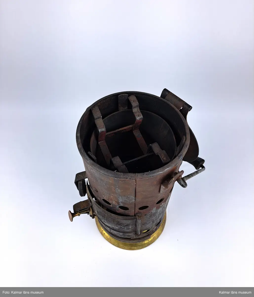 KLM 46808:9:1-2. :1. Smältugn, lödugn, med smältdegel. Cylindrisk smältugn av plåt med lock, handtag och lucka på framsidan. På luckan tillverkarstämpel: MAX SIEVERT STOCKHOLM. Underdel av mässing. På handtaget en krok för upphängning. Inuti en uttagbar insats av metall. 
:2. Smältdegel av gjutjärn med rund form och handtag. På handtaget en skruvögla för upphängning. På degelns kanter tillverkarstämpel: MAX SIEVERT STOCKHOLM SWEDEN. Har troligtvis använts för smältning av exempelvis metall för lagning av elkablar och eventuellt annat på järnvägsspåret.