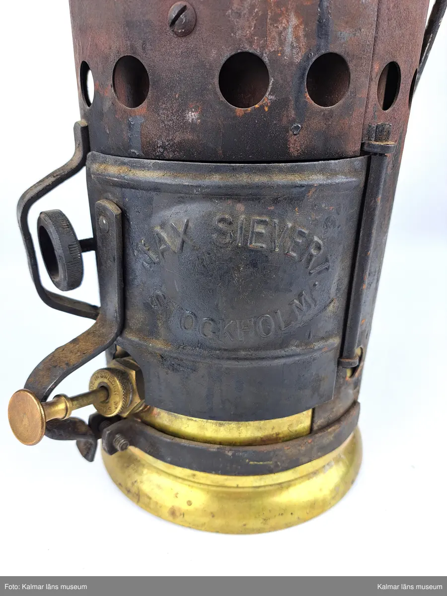 KLM 46808:9:1-2. :1. Smältugn, lödugn, med smältdegel. Cylindrisk smältugn av plåt med lock, handtag och lucka på framsidan. På luckan tillverkarstämpel: MAX SIEVERT STOCKHOLM. Underdel av mässing. På handtaget en krok för upphängning. Inuti en uttagbar insats av metall. 
:2. Smältdegel av gjutjärn med rund form och handtag. På handtaget en skruvögla för upphängning. På degelns kanter tillverkarstämpel: MAX SIEVERT STOCKHOLM SWEDEN. Har troligtvis använts för smältning av exempelvis metall för lagning av elkablar och eventuellt annat på järnvägsspåret.