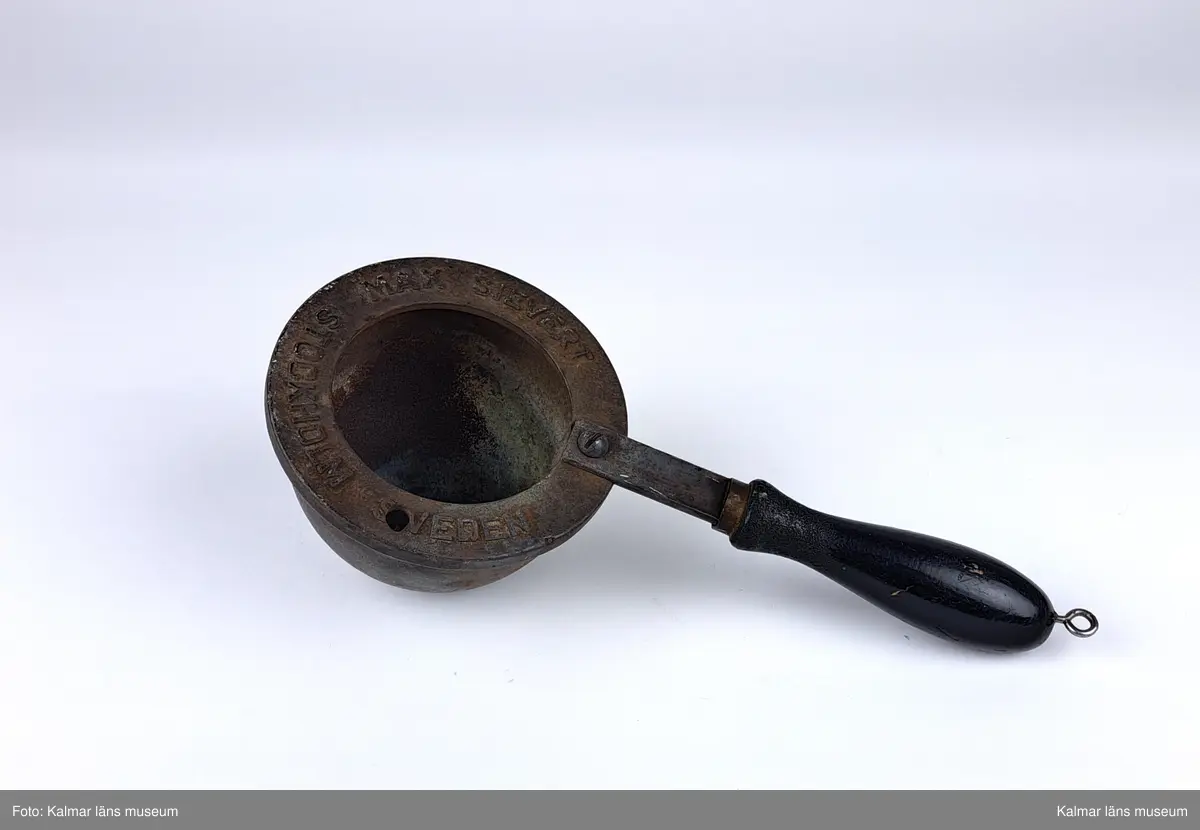 KLM 46808:9:1-2. :1. Smältugn, lödugn, med smältdegel. Cylindrisk smältugn av plåt med lock, handtag och lucka på framsidan. På luckan tillverkarstämpel: MAX SIEVERT STOCKHOLM. Underdel av mässing. På handtaget en krok för upphängning. Inuti en uttagbar insats av metall. 
:2. Smältdegel av gjutjärn med rund form och handtag. På handtaget en skruvögla för upphängning. På degelns kanter tillverkarstämpel: MAX SIEVERT STOCKHOLM SWEDEN. Har troligtvis använts för smältning av exempelvis metall för lagning av elkablar och eventuellt annat på järnvägsspåret.