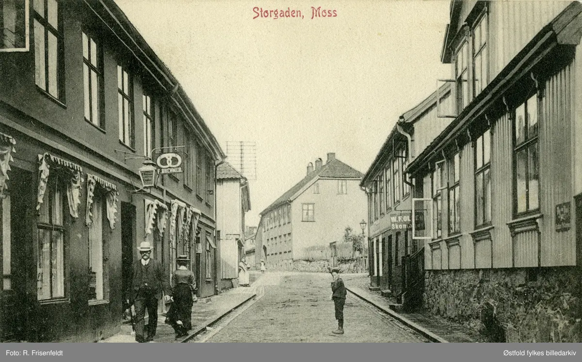 Storgata i Moss ca. 1910.  Til venstre F. Brehmer Bageri & Conditori i Storgata 16 ca. 1910. Til høyre skomaker W. F. Olsen. 
Heiberggården i bakgrunnen, seinere Moss Handelstands Forenings bygning. Postkort.