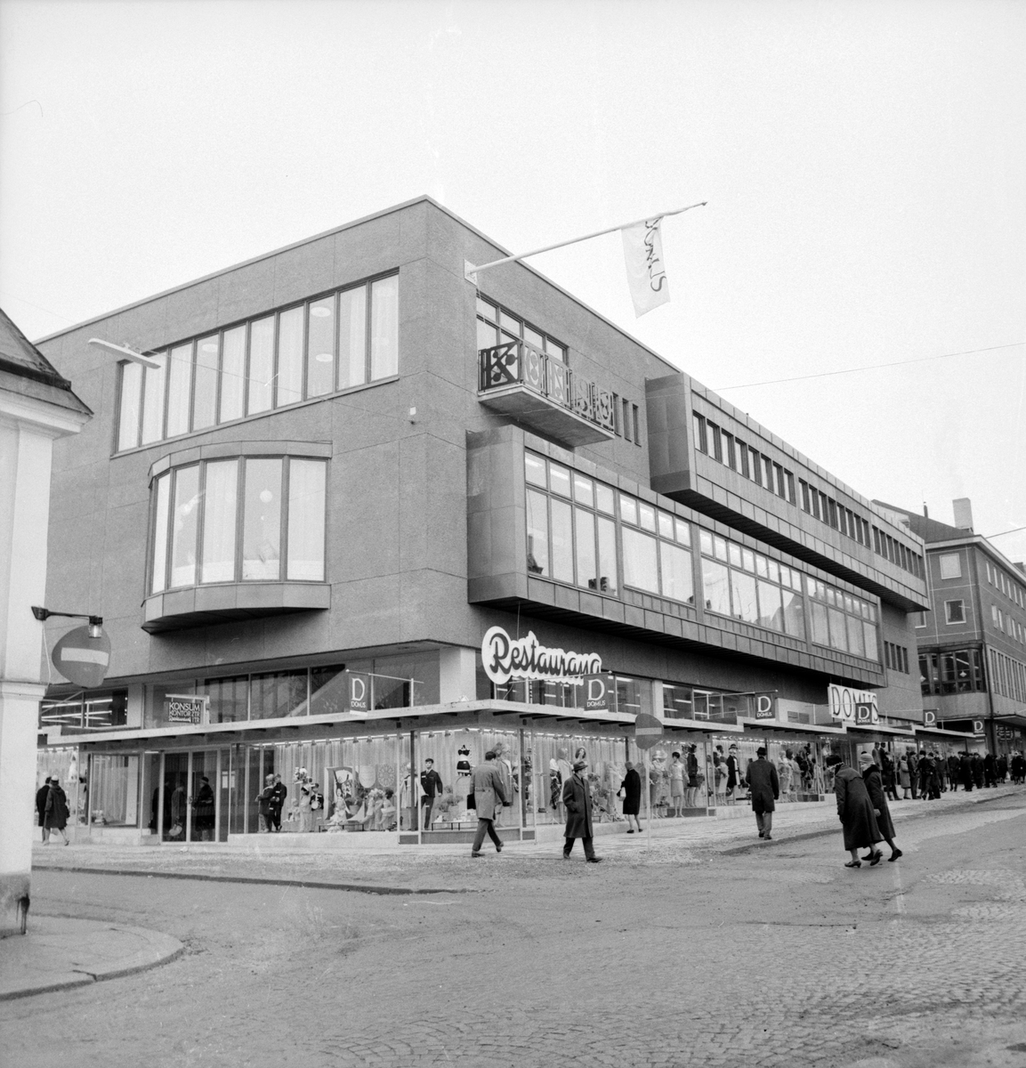 Kooperativa förbundets nya varuhus i Linköping nära öppnadet våren 1966. För ritningarna stod förbundets egna arkitekt- och ingenjörskontor, KFAI, och följde tidens närmast mönsterritade handelshus. Som en lätträknad utsmyckning kan övre våningens balkongräcket räknas med "KONSUM" i sirligt smide.