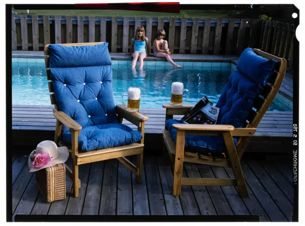 Fåtöljer på ett trädäck framför en pool.