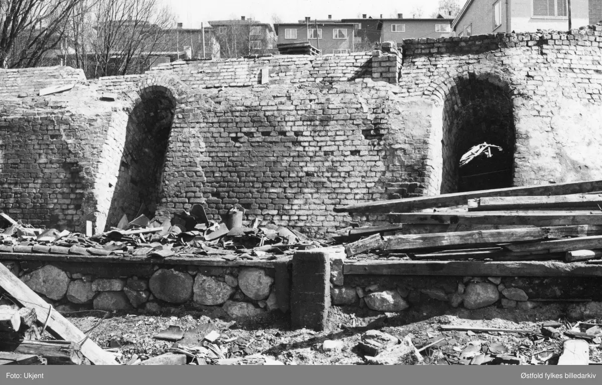 Moss teglverk i Moss rives, mai 1966.  Moss teglverk og kalkverk ble etablert 1896 nederst på Melløsjordene, driften opphørte 1919. Selve bygningene ble revet i 1940, og her er det siste rest av teglverket som blir revet. Fjordveien i bakgrunnen.