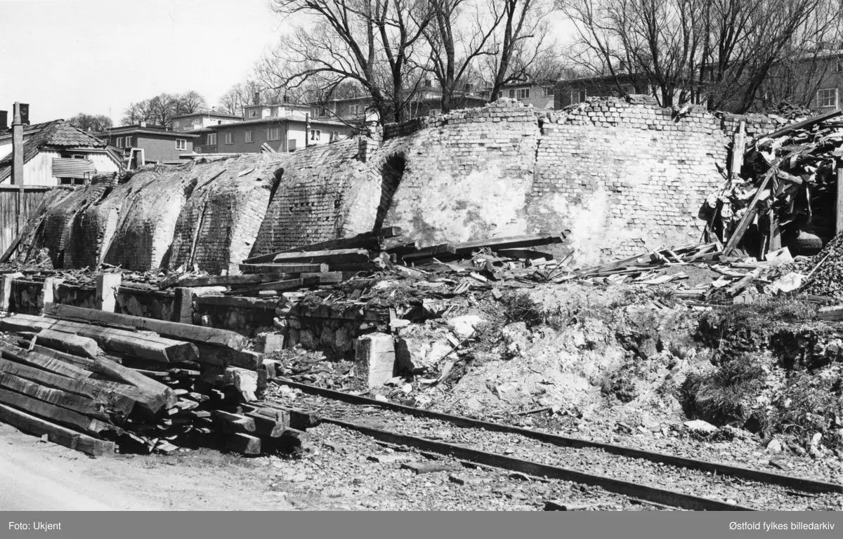 Moss teglverk i Moss rives, mai 1966.  Moss teglverk og kalkverk ble etablert 1896 nederst på Melløsjordene, driften opphørte 1919. Selve bygningene ble revet i 1940, og her er det siste rest av teglverket som blir revet. Fjordveien i bakgrunnen.