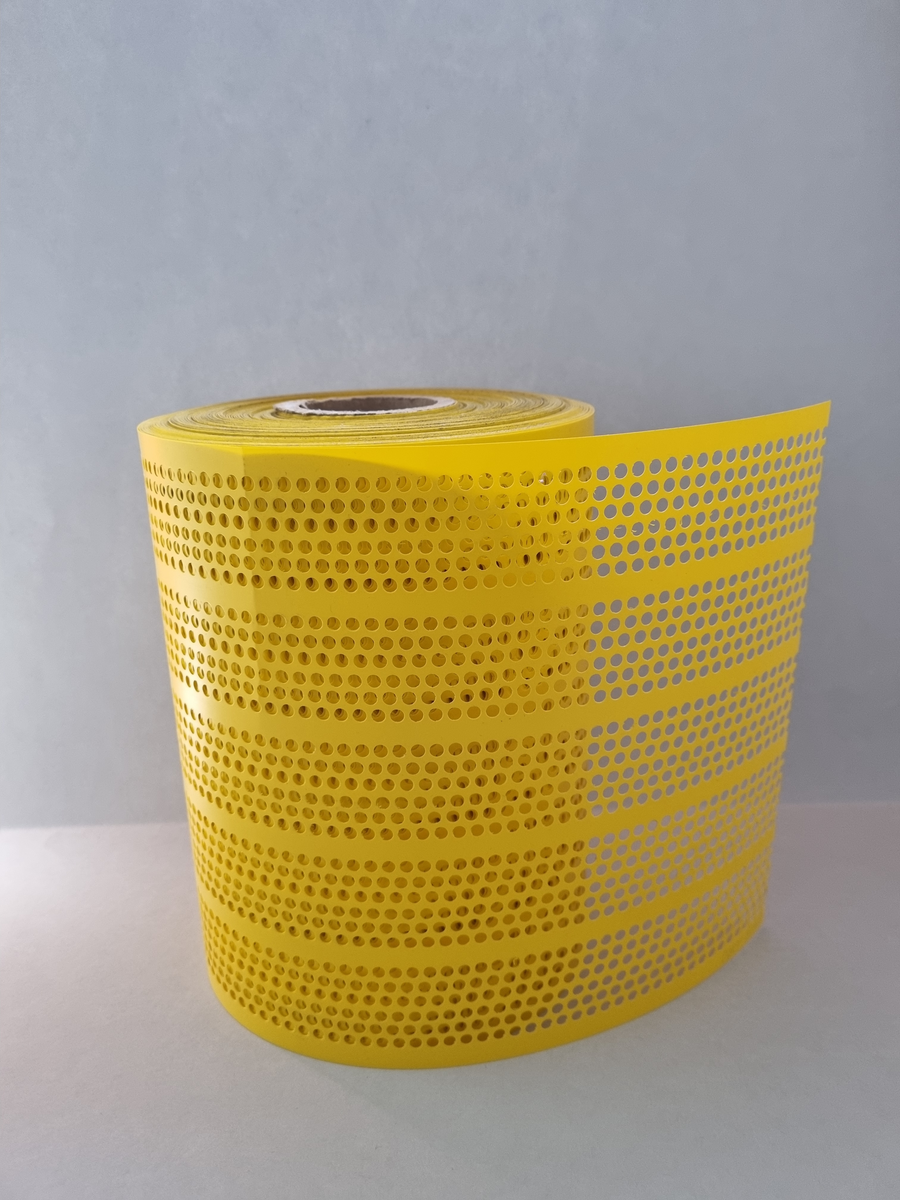 Rulle med utstansade prickar som suttit i majblommemaskin. Restprodukt efter utsansad mittprick.
