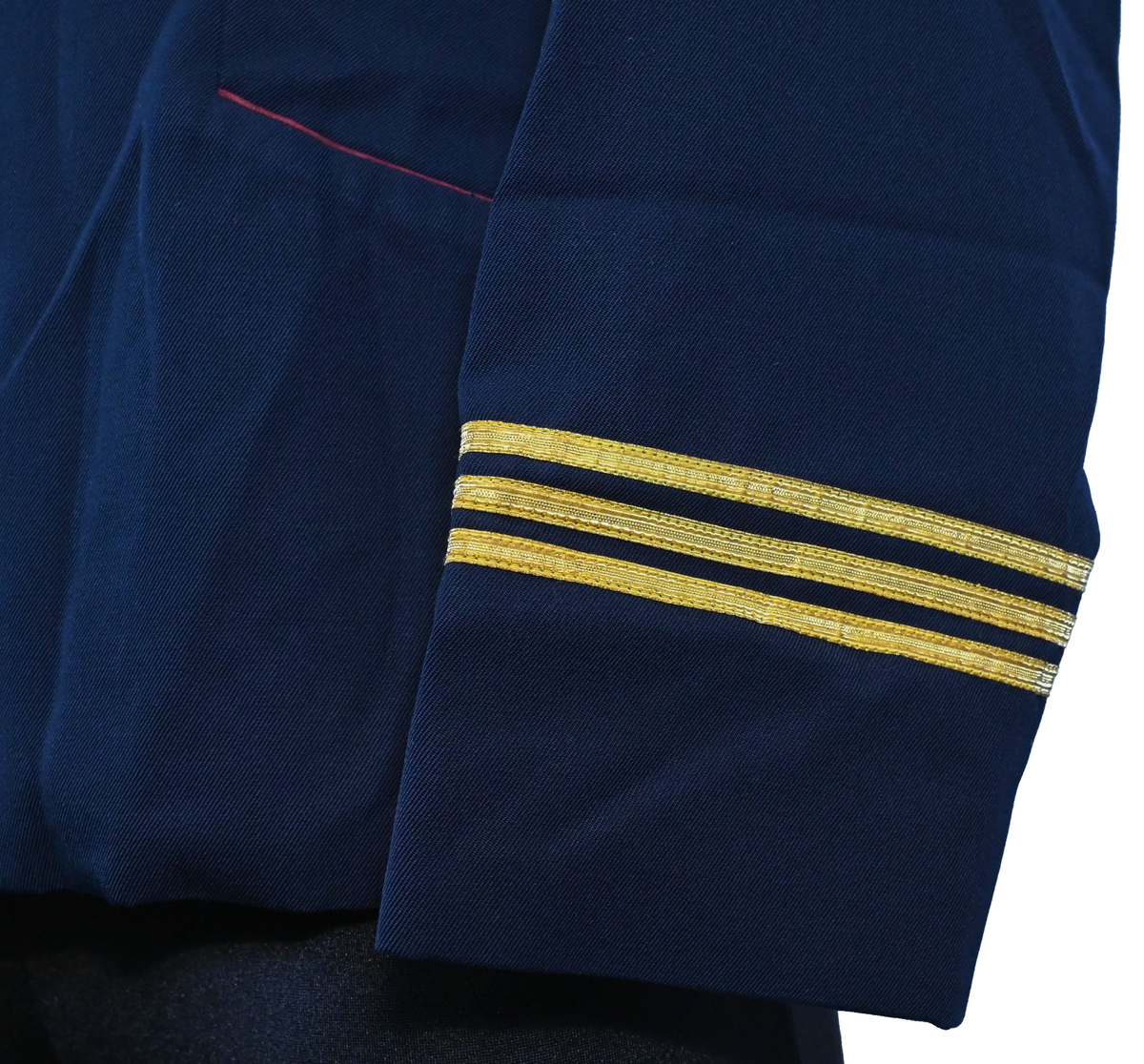 Kavaj, uniform, dammodell. Mörkblå tyg av 80% ull och 20 % polyester. Enkelkläppning med två guldfärgade knappar och tre rader av guldgaloner vid vardera ärmslut. Två midjefickor och en bröstficka på vänster sida. Kavajslaget och fickornas kanter har vinröda passpoaler. Design av Getti S.P.A.