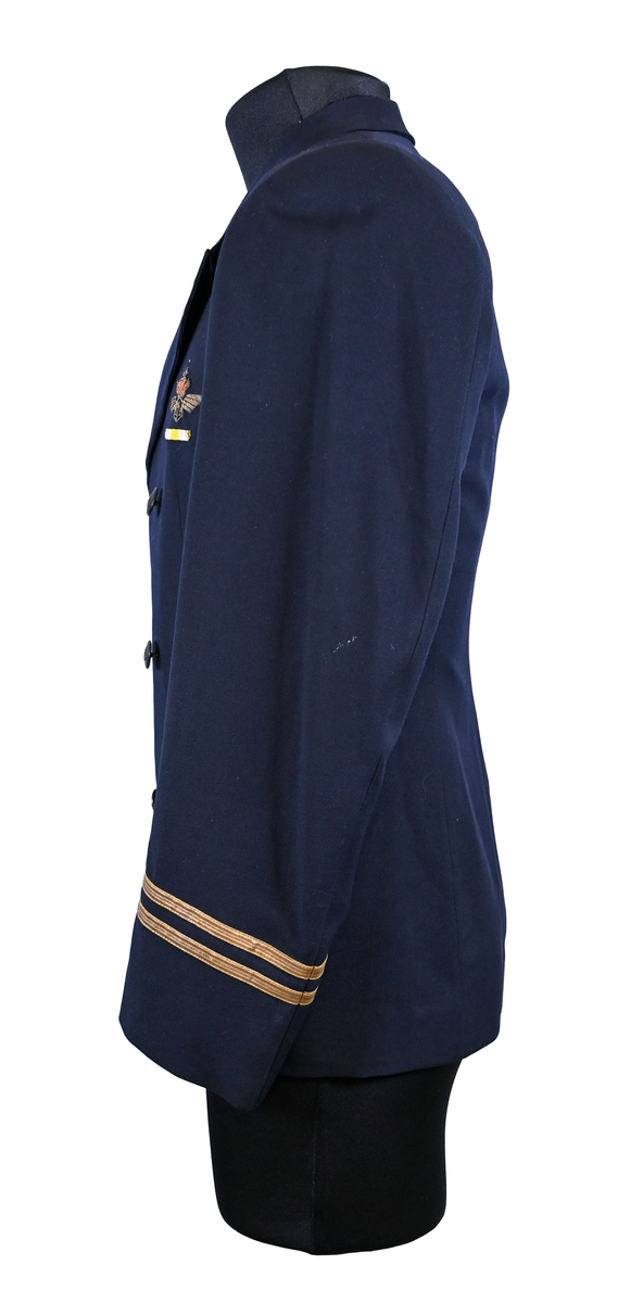 Kavaj i herrmodell, uniform från flygbolaget KLM Royal Dutch Airlines. Har tidigare tillhört Carl Gustaf Von Rosen. Mörkblå ylle med dubbelknäppning. Med KLMs emblem på vänster sida samt två galoner vid var ärmslut.