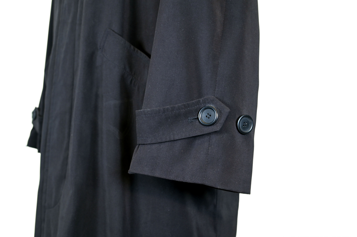 Fodrad överrock i trenchcoat-modell för flygbolagspersonal hos Delta Air Lines. Rocken har två ytterfickor samt en innerficka. Rocken består av skalrock samt löstagbart foder genom dragkedja. Både skalrock och foder är svarta och skalrocken är sydd med raglanärm. Enkel knäppning med fem svarta plastknappar samt två svarta plastknappar vid vardera ärmslut.

Storlek 42 R