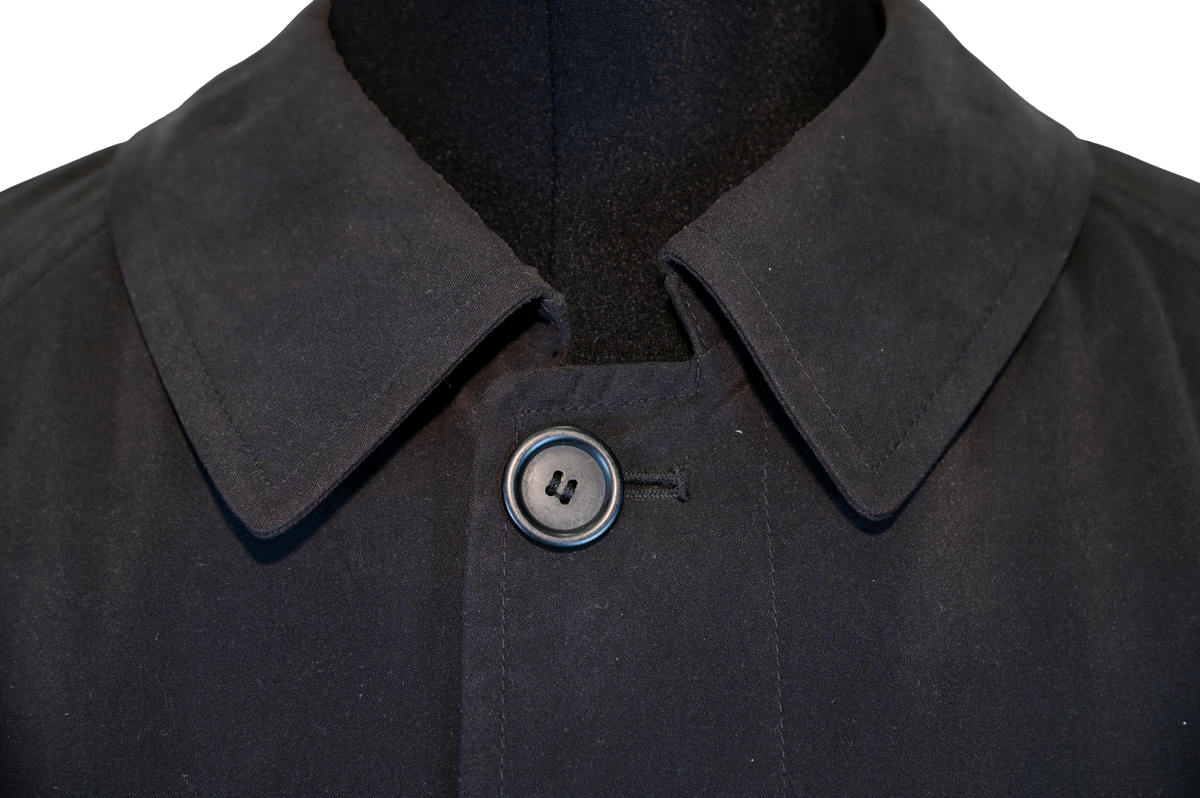 Fodrad överrock i trenchcoat-modell för flygbolagspersonal hos Delta Air Lines. Rocken har två ytterfickor samt en innerficka. Rocken består av skalrock samt löstagbart foder genom dragkedja. Både skalrock och foder är svarta och skalrocken är sydd med raglanärm. Enkel knäppning med fem svarta plastknappar samt två svarta plastknappar vid vardera ärmslut.

Storlek 42 R