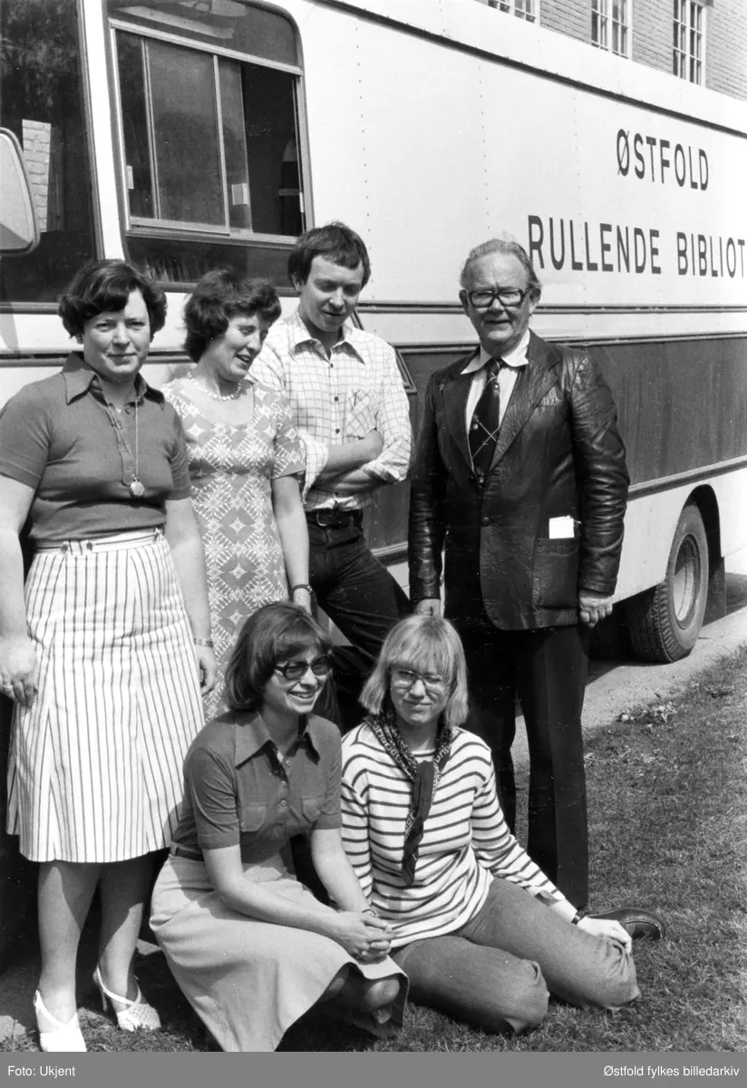 Østfold fylkesbibliotek, ansatte utenfor bokbussen, Østfold rullende bibliotek. Bokbussjåfør Viggo Nilsen bakerst til høyre. Viden siden av Han Svein E. Nilsen. På huk foran til venstre distriktsbibliotekar Irene Bergmann.