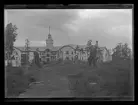 Bilden visar två män som tagit uppställning för fotografering framför Voksenkollen sanatorium i Oslo. Byggnaden brann ner 1919.