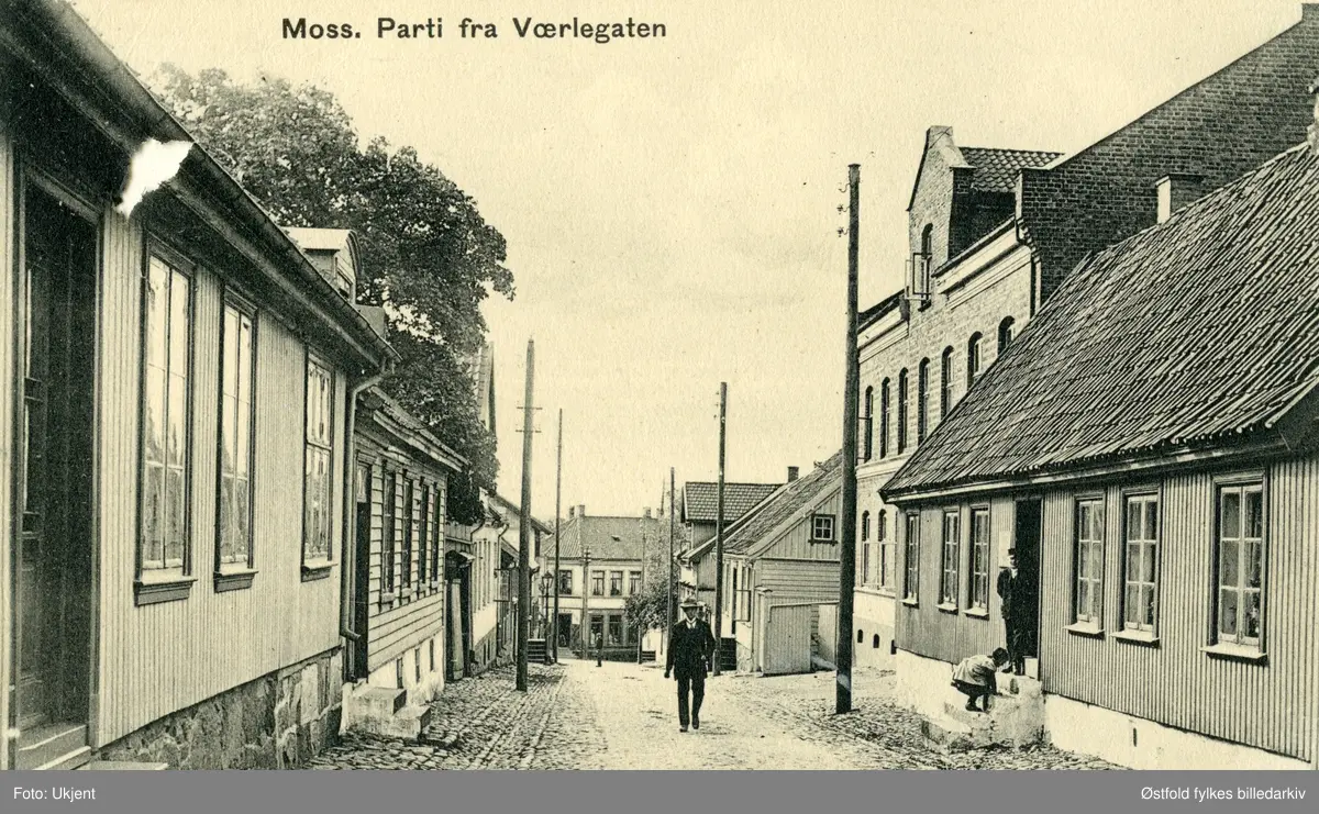 Gateparti fra Værlegata i Moss, postkort ca. 1910. Til høyre Agnalt-gården, bygd 1825. Den store murbygningen er fra 1878. Gården til venstre ble bygd 1856. og gårdene nedenfor i 1830-åra. Barn på trappa.