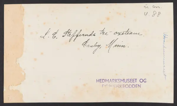 Tre okser spent foran en vogn. Til venstre et hus bygd av jo