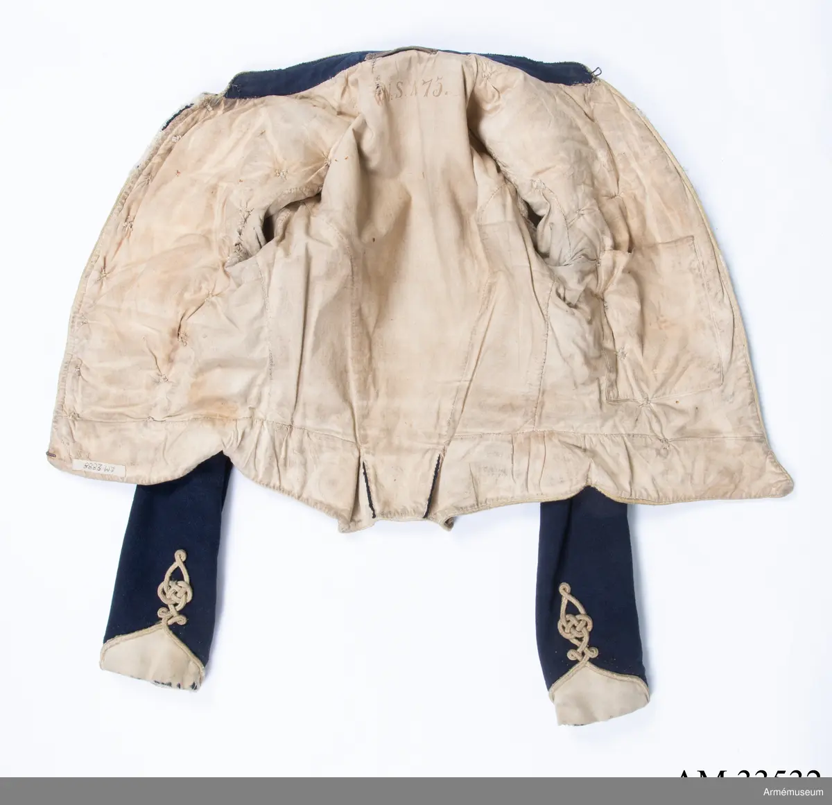 Blå dolma m/1846 med platta vita snören m/1851.

Dolman är sydd av mörkblått kommisskläde, med liten ståndkrage och ärmuppslag av vitt kläde. Helfodrad med vitt bomullstyg.
Plagget är kroppsnära, och är konstruerat med fram- och sidstycken i ett, sidstycken bak, samt helt bakstycke som går ner i en avkapad spets mitt bak. Det har midjesöm och litet skört som fortsätter bak och bildar veck vid sidsömmen. Ärmarna är ensömsärmar eller S-ärmar med fasta vita ärmuppslag som slutar i en spets upptill, och har ärmsprund som knäpps med hysk och hake.
Tvärs över bröstet löper 8 rader med snörmakerier med 3 lodräta knapprader med 8 knappar i varje. De yttre raderna har kullriga nappar medan mittenraden har klotknappar. Samtliga knappar är av mässing. Snörmakerierna är gjorda av vita fyrkantsnören, så kallade platta snören, av ull.
Plagget bär spår av att vara omsytt; bland annat är ärmarna förlängda nertill och en lång kil är iskarvad från ärmhålet till underärmen på båda ärmar. Framtill syns iskarvade kilar nertill. Det är även hårt slitet, och har flera lagade revor som uppstått under dess användningstid samt ett lappat hål på vänster ärmkulle framtill.
Innerficka i vänster framstycke, samt bröstfickor på båda sidor på utsidan, dolda under snörmakerierna.
Plagget är märkt för hand med skrivstil i ryggens fodersida, med bokstäverna W:N:S No 73, vilket troligen står för Westra Närkes Skvadron, soldatnummer 73.
På baksidan pryds dolman av snören längs med sidsömmarna som slutar i en knut upptill, samt med snörmakerier på skörtet, bland annat i form av en spiral. Även dolmans nederkant, framkant och ärmarnas nederkant pryds av snören.