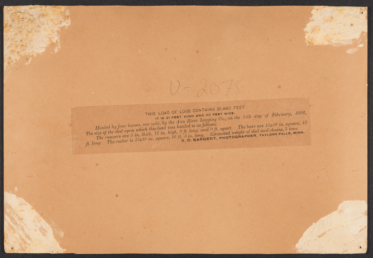 Tømmerlass. Fire hester. Fire mann ved siden av lasset. En stokk på lasset merket "31480".
USA.  Tidspunkt: 13.2.1892.
Evt. gave til museet.
Flere opplysninger på andre kartotekkort.

THIS LOAD OF LOGS CONTAINS 31,480 FEET
it is 21 feet high and 20 feet wide.

Hauled by four horses, one mile, by the Ann River Logging Co., on
the 13th day of February, 1892. The size of the sled upon which this
load was hauled is as follows:
The runners are 5 in thick, 11in. high, 9 ft. long,and 9 ft. apart.
The bars are 15x18 in. square, 12 ft. long. The rocker is 15 x 18 in.
square, 16 ft. 3 in. long. Estimated weight of sled ard chains, 5 tons:
S. C.. SARGENT, PHOTOGRAPHER, TAYLORS FALLS, MINN.
