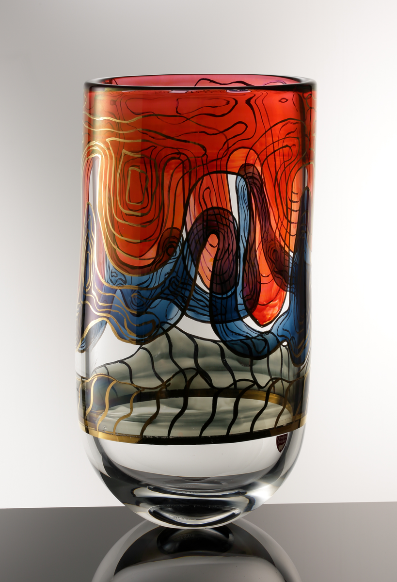 Formgivare: Jan Johansson. Cylindrisk vas i ofärgat glas med rundad bas. Målad abstrakt dekor i rött, blått och gråsvart, mönsterslingor i guld.