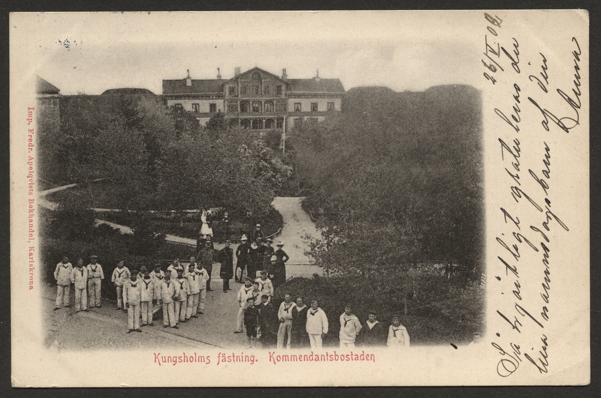 Vykort visar flottister i sommaruniform på Kungsholms fästning. I bakgrunden syns kommendatsbostaden.